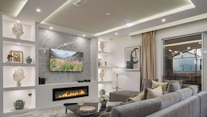 A modern living room with a fireplace, a large flat-screen TV, and a sofa. - Escape to Luxury: Magical 10-bedroom Villa Near Disney World! (Davenport)
