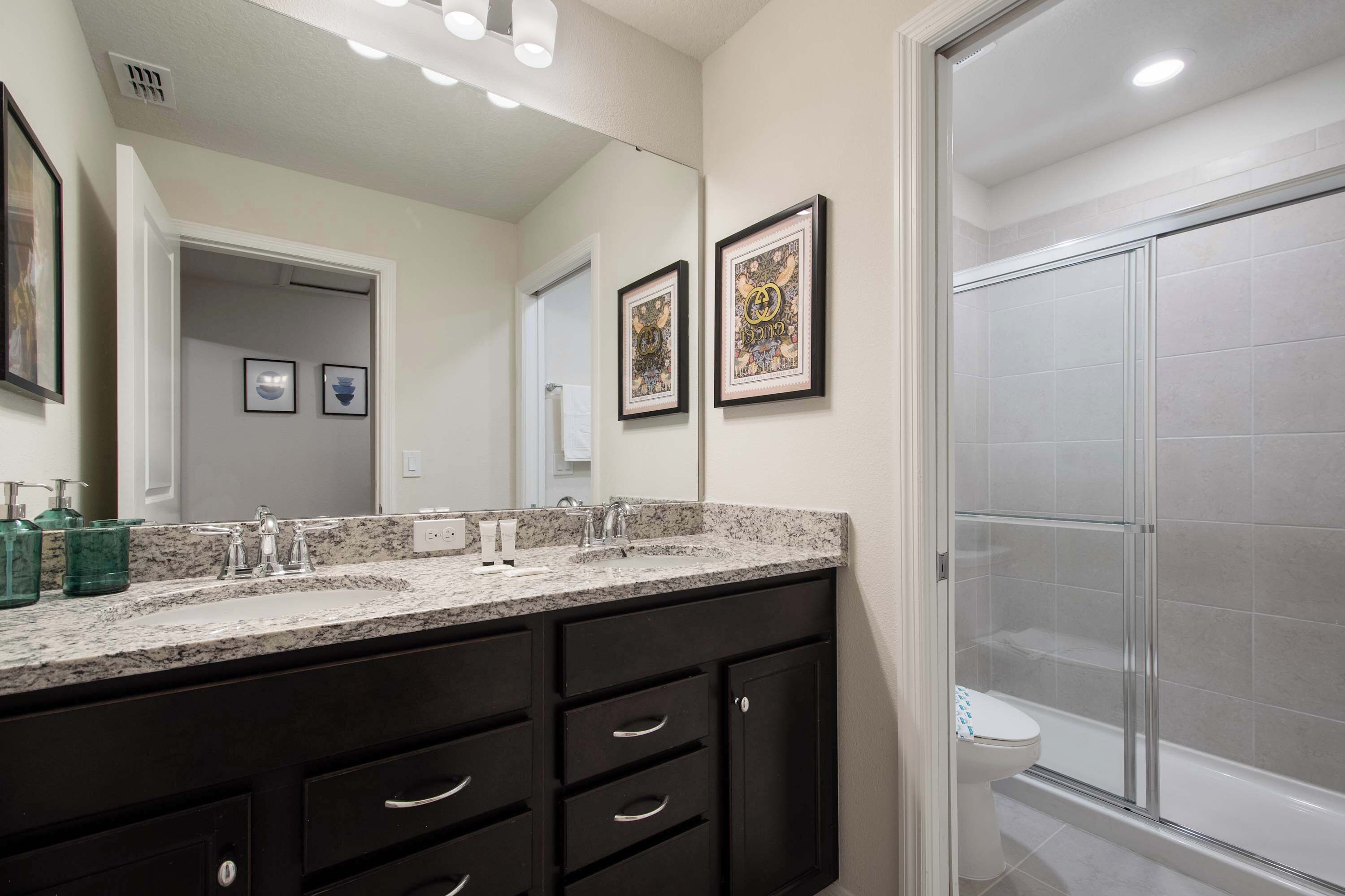 A bathroom with a double vanity, a large mirror, and a glass shower enclosure.