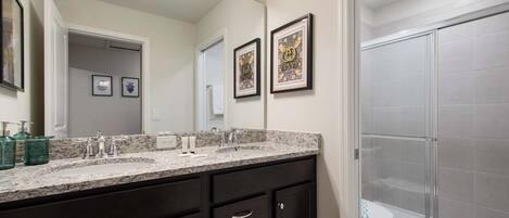 A bathroom with a double vanity, a large mirror, and a glass shower enclosure.