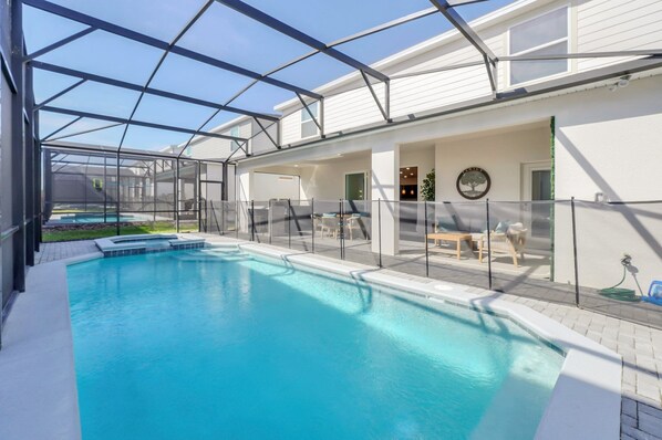 A swimming pool with a glass enclosure, a covered patio area with seating, and a view of the backyard. - 2 Slides • Star Wars Theater • Mario Kart Game Room • Princess Castle (Clermont)