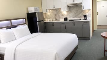 Une chambre d’hôtel avec un lit, une kitchenette et une petite table.