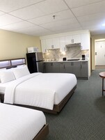 A hotel room with a bed, a kitchenette, and a small table.