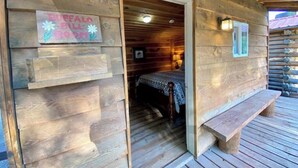 A wooden cabin with a bed, a bench, and a sign reading "Buffalo Bill Room." - Buffalo Bill Cabin At Mountain River Ranch (Ririe)