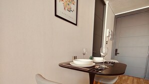 A dining area with a table set for two, a framed picture on the wall, and a door leading to a garage. - Confort de Fray Camilo 171 (Santiago)