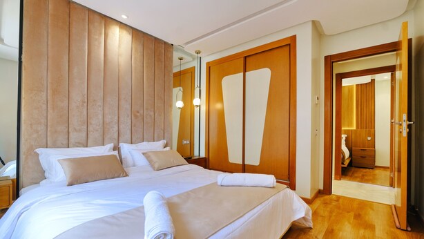 Quarto de hotel com uma cama grande, cabeceira de madeira e um espelho.