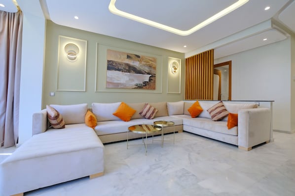 A modern living room with a sectional sofa, a glass coffee table, and a painting on the wall.