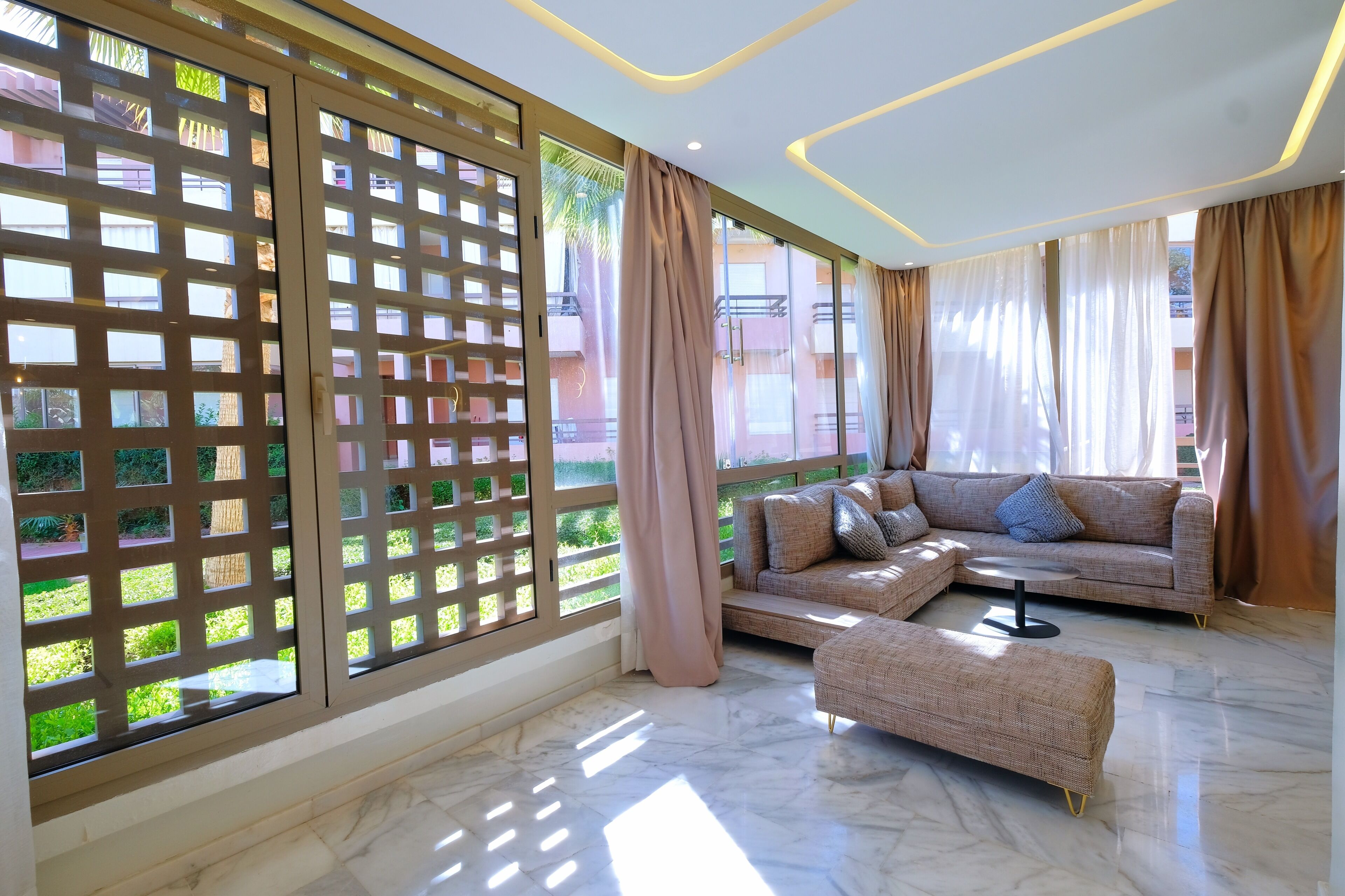 A modern living room with a sectional sofa, a small round table, and a decorative screen.