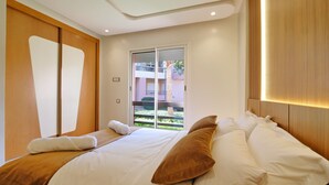 Quarto de hotel moderno com uma cama grande, uma porta deslizante e vista para o exterior.
