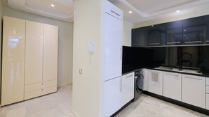Uma cozinha moderna com armários brancos, bancada preta e forno embutido.