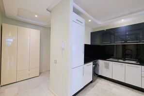 A modern kitchen with white cabinets, a black countertop, and a built-in oven.