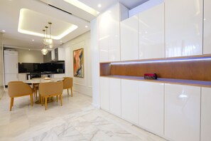 A modern kitchen with white cabinetry, a dining area with a marble table, and a built-in bench with a red cushion. - Calm and luxury (Marrakech)