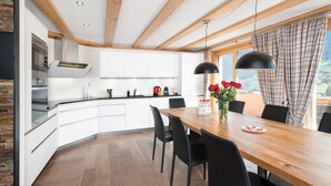 A modern kitchen with white cabinets, a wooden dining table, and black chairs.
