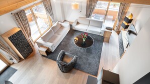 A modern living room with a sofa, armchairs, a coffee table, and a fireplace.
