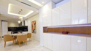 A modern kitchen with a dining area, white cabinetry, and a marble floor.