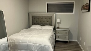 Ein Schlafzimmer mit Bett, Nachttisch und Fenster.