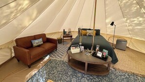 A tent with a bed, a sofa, a lamp, and a small table.
