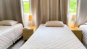 A hotel room with two single beds, each with a pillow and a bedside table with a lamp.