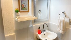 A bathroom with a white sink, a mirror, a towel rack, and a framed picture on the wall.