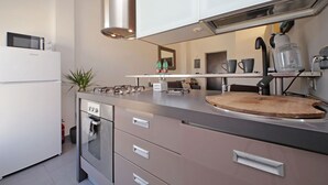 A modern kitchen with stainless steel appliances, a wooden cutting board, and a coffee maker.