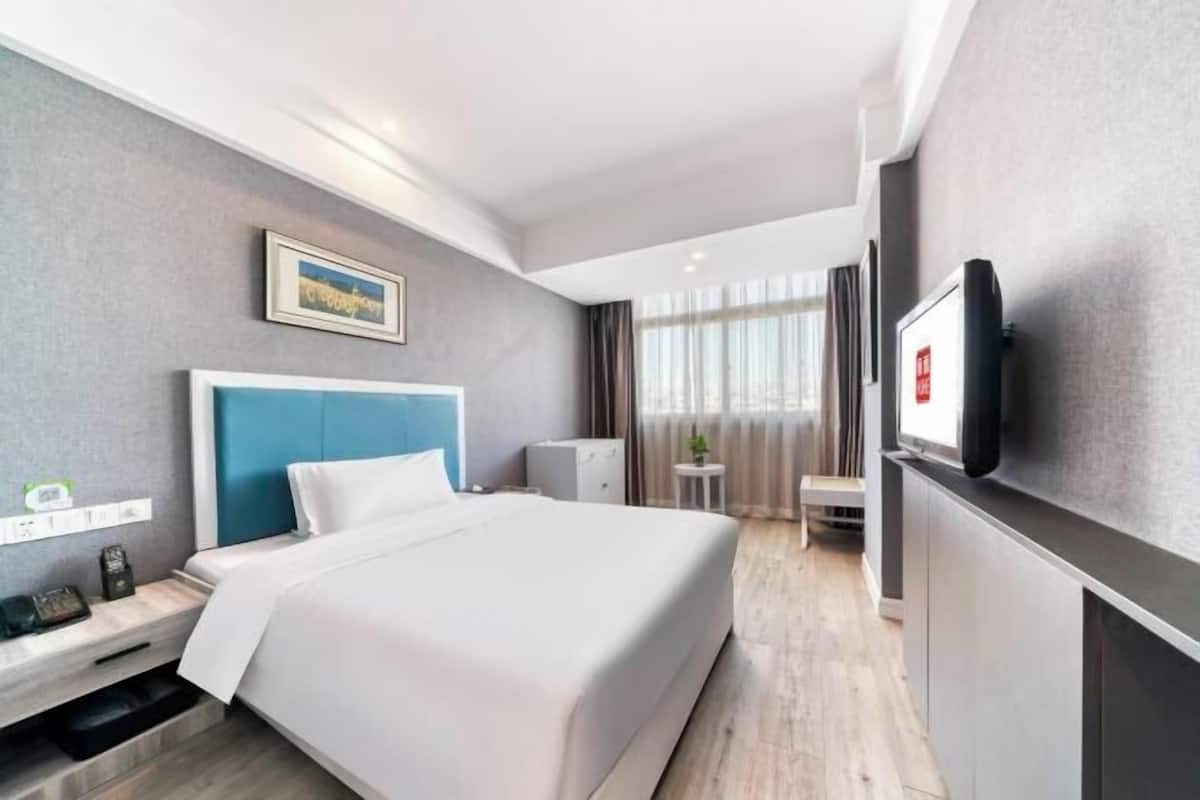 Une chambre d’hôtel avec un lit, une télévision, un bureau et une petite table.