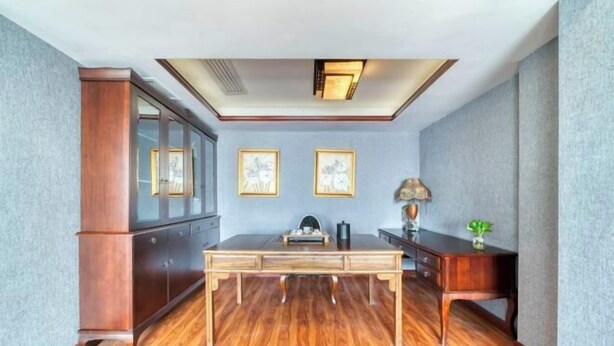A room with a wooden floor, a desk, a cabinet, and two framed pictures on the wall. - Huihe Hotel (Shangrao High Speed Railway Station) (Shangrao)
