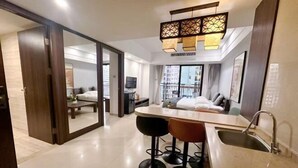 Una habitación de hotel moderna con área de cocina, una mesa de comedor y un ventanal grande.