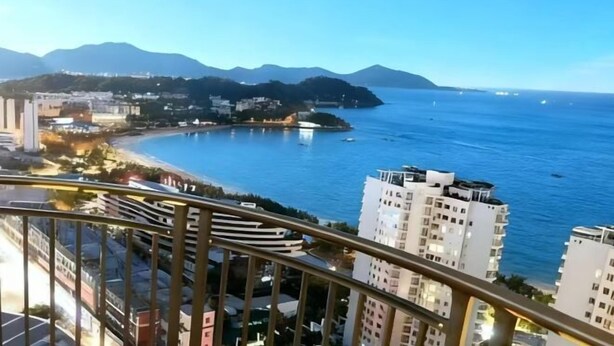 Un paisaje costero con edificios altos, una playa y montañas al fondo.