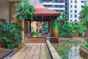 A covered outdoor area with steps leading to a building entrance, surrounded by greenery and a water feature. - Sanya Dadonghai Gediao House Apartment (Sanya)