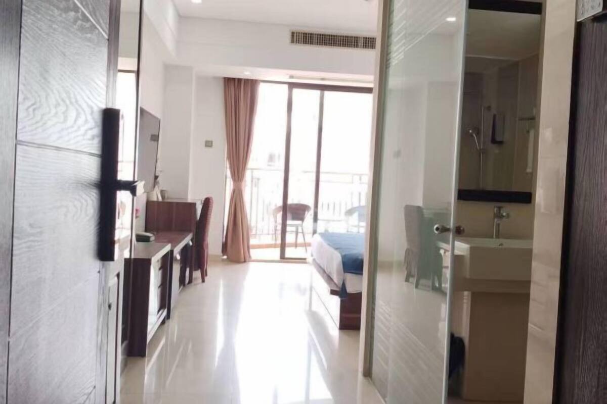 Ein Hotelzimmer mit Bett, Schreibtisch, Stuhl, Badezimmer mit Waschbecken und Spiegel sowie einem Balkon mit Blick.