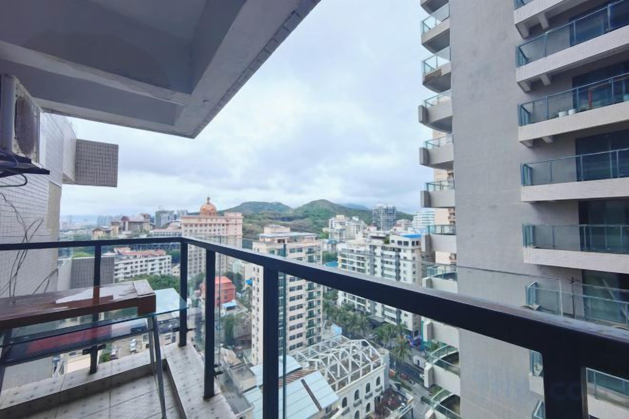 Un balcón con vistas a un paisaje urbano, incluyendo edificios y una montaña.