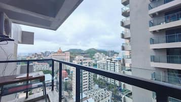 Un balcón con vistas a un paisaje urbano, incluyendo edificios y una montaña.