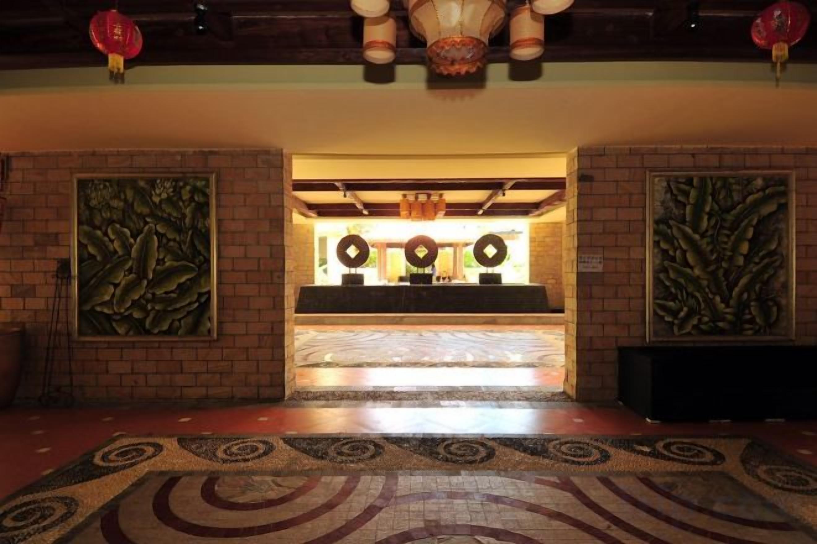A lobby with a reception desk, patterned carpet, and decorative wall art.
