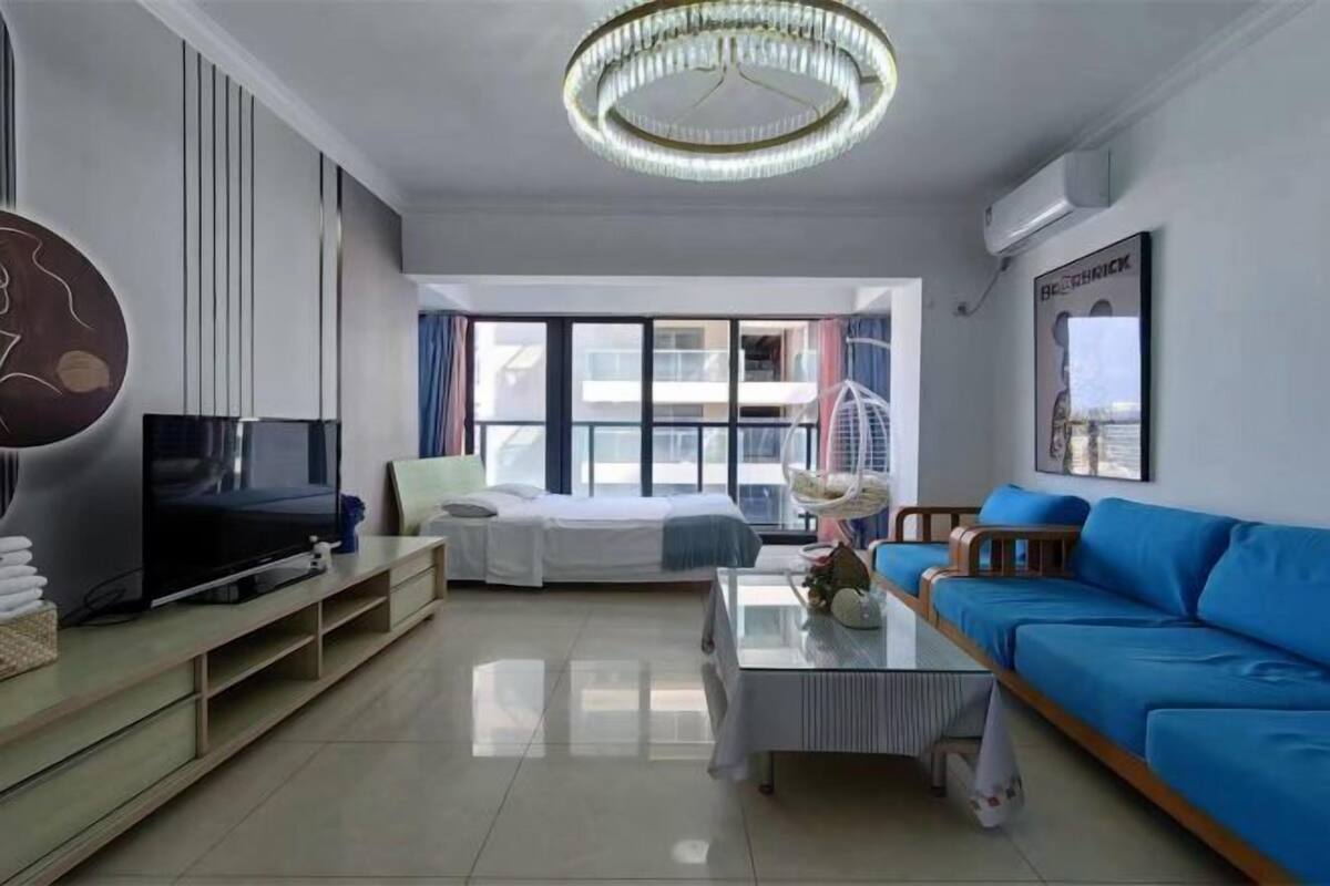 Ein modernes Wohnzimmer mit Fernseher, Sofa und einem großen Fenster.