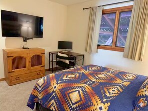 A bedroom with a bed, a TV, a desk, and a window with curtains. - 5 Min. Free Shuttle to Resort•Mountain Views•Hot Tub•Sauna•Private Garage (Crested Butte)