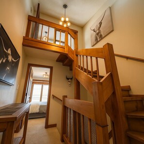 A wooden staircase with a glass enclosure leading to a second-floor landing. - 5-Min Free Shuttle to Lifts•Mountain Views•Hot Tub•Sauna•Private Garage (Crested Butte)
