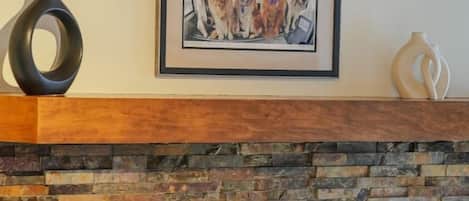 A fireplace with a stone surround, a framed picture above it, and two leather ottomans.
