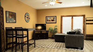 A living room with a dining table, chairs, a sofa, a TV, and a ceiling fan. - Cozy 1-bedroom apartment in quaint Creedmoor with AC, WiFi &laundry (Creedmoor)