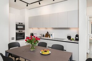 A modern kitchen with built-in appliances, a dining area with a table and chairs, and a vase with flowers.