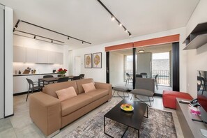 A modern apartment with a living room, dining area, kitchenette, and a balcony.