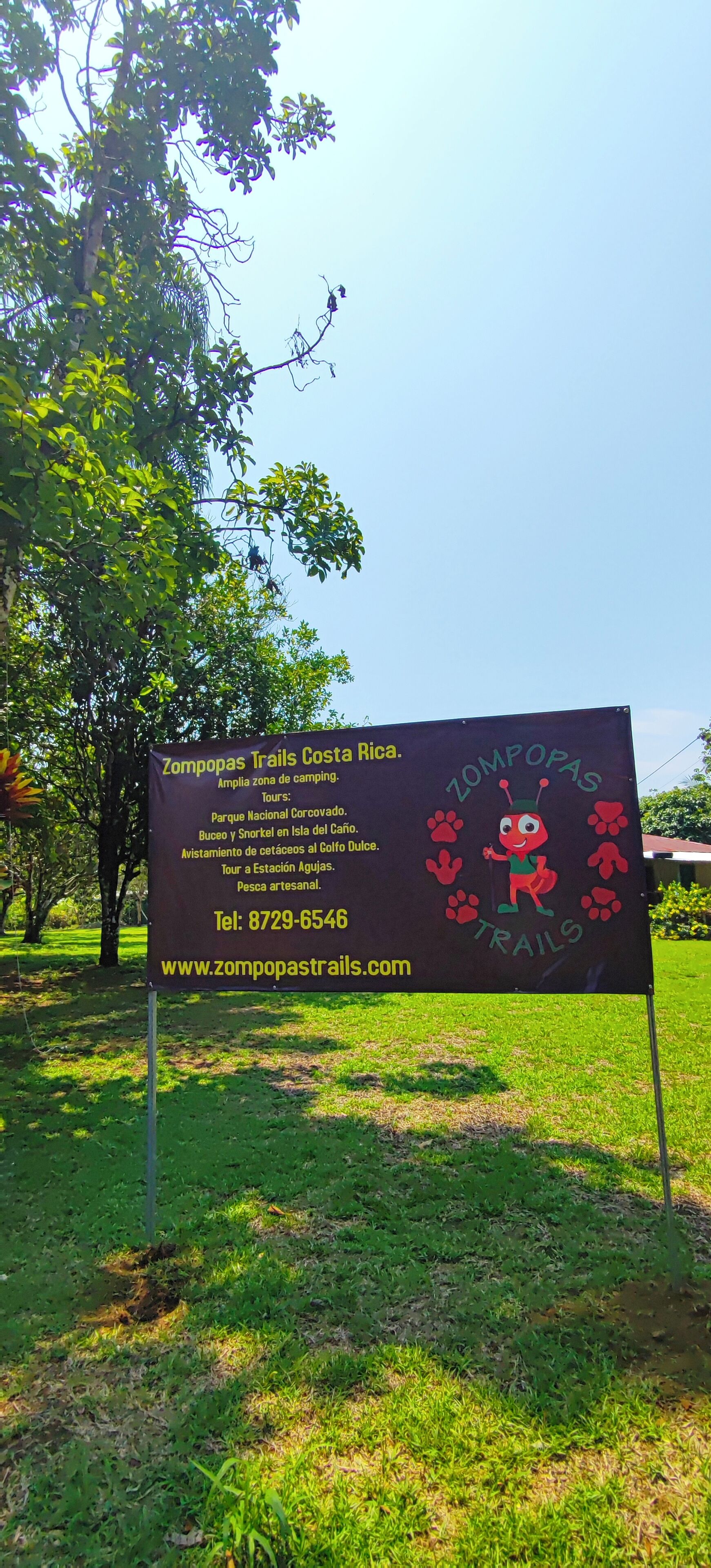 En skylt för vandringslederna i Zompopas, Costa Rica, med information om guidade turer och kontaktuppgifter.