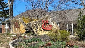 Un rocher portant l’inscription « The Club », entouré d’un jardin aménagé avec différentes espèces de plantes.