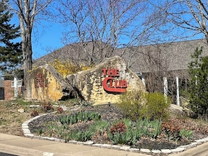 Un rocher portant l’inscription « The Club », entouré d’un jardin aménagé avec différentes espèces de plantes.