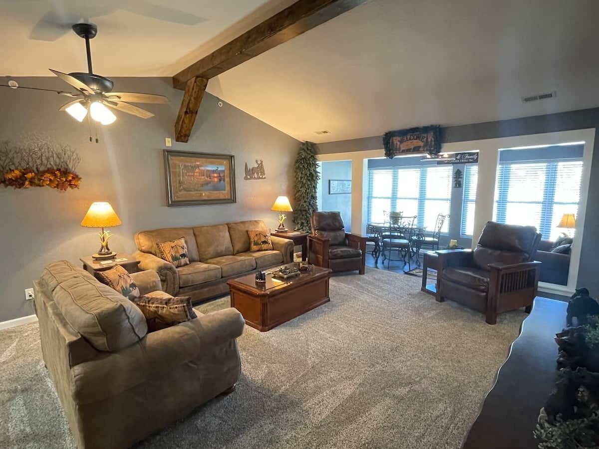 A living room with a ceiling fan, a sofa set, a coffee table, and a dining area with a table and chairs.