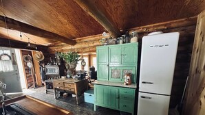 A rustic kitchen with wooden beams, a vintage refrigerator, and a green cabinet.