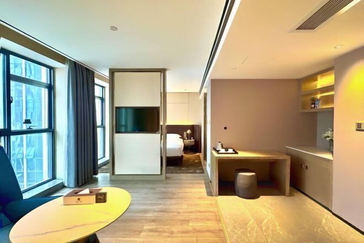 Une chambre d’hôtel moderne avec une grande fenêtre, un bureau, une chaise et un lit.