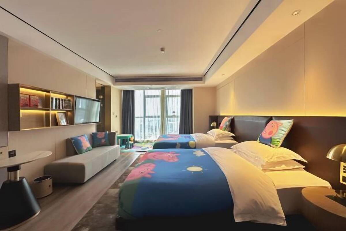 Une chambre d’hôtel moderne équipée de deux lits, d’un canapé, d’une télévision et d’un bureau.