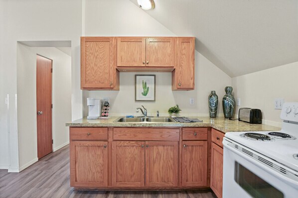 A compact kitchen with wooden cabinets, a built-in oven, and a coffee maker. - Maple Manor City View (Spokane)