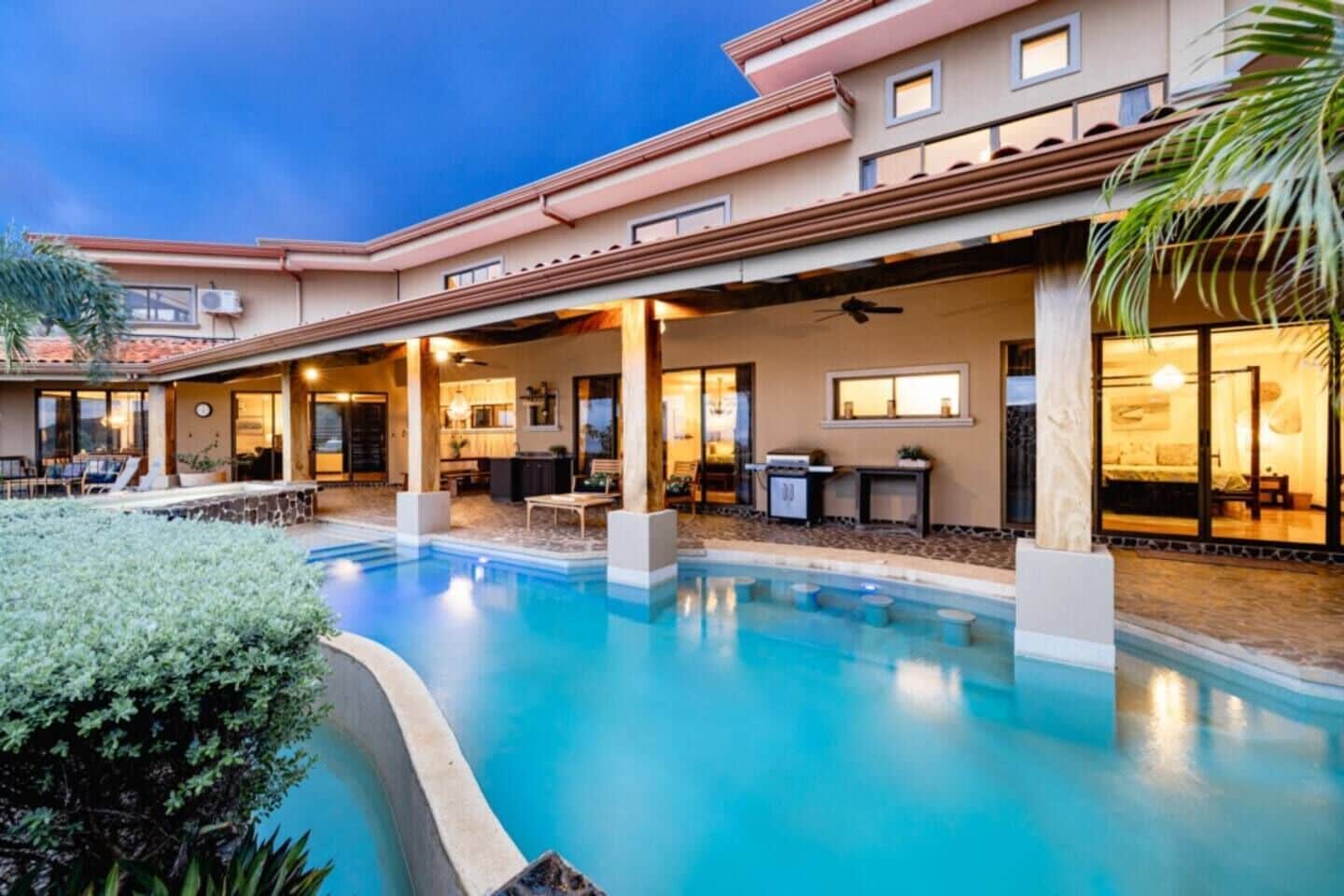 Un hotel con piscina, mobiliario exterior y un patio cubierto.