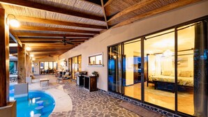 Un área de piscina con suelo de piedra, un bar y un dormitorio con cama y mesita de noche.