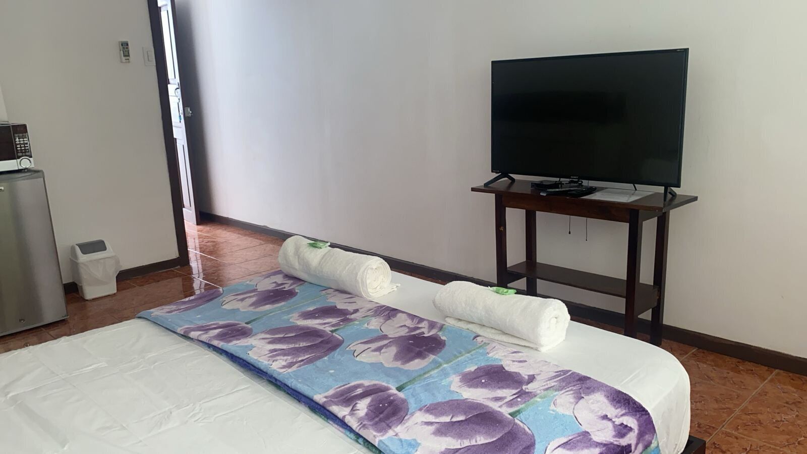 A hotel room with a bed, a television on a stand, and a small table.
